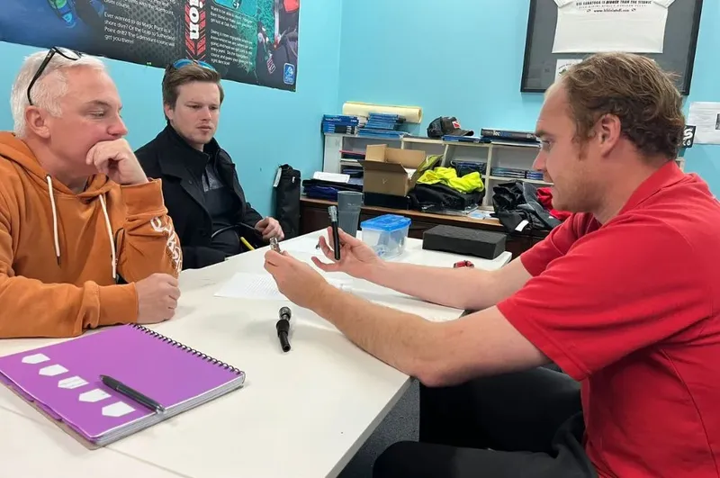 Trois personnes discutent autour d'une table dans un bureau avec du matériel