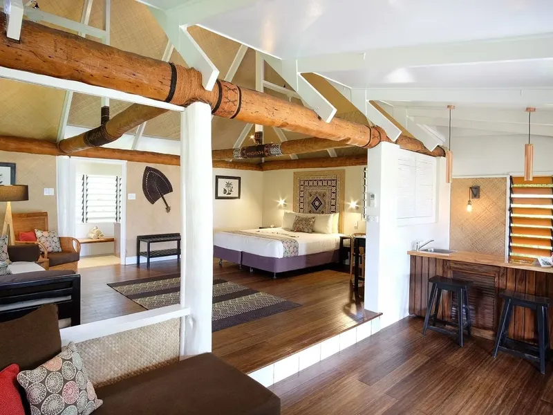Intérieur d'une chambre avec salon, lit et bar, décoration tropicale