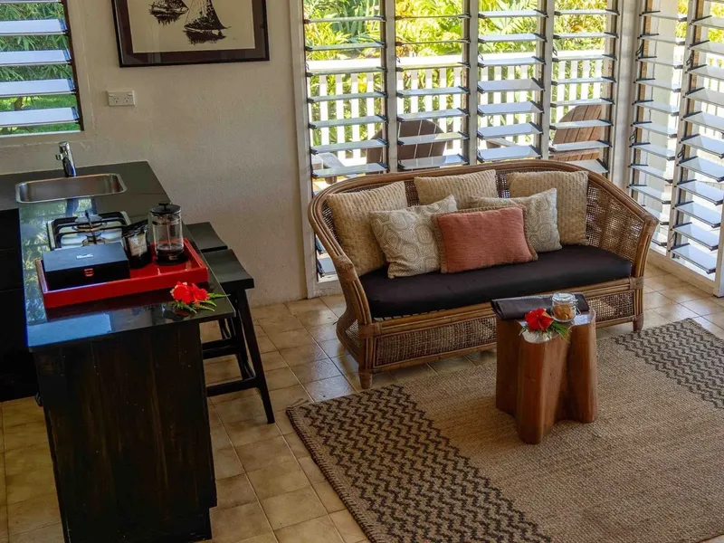 Intérieur lumineux avec coin cuisine, canapé en rotin et vue sur l'extérieur