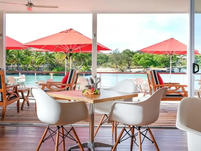 Terrasse avec tables et parasols rouges vue sur l'eau