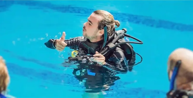 Plongeur en formation dans une piscine, signe OK, équipement complet