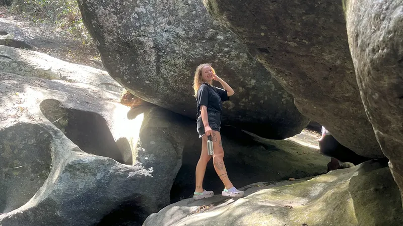 Jeune femme souriante se tient entre de gros rochers gris