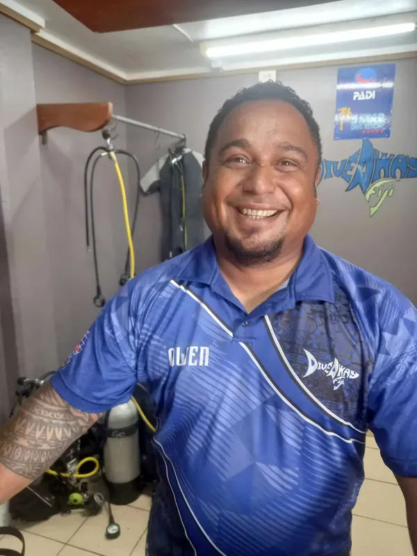 Homme souriant avec équipement de plongée devant un mur décoré