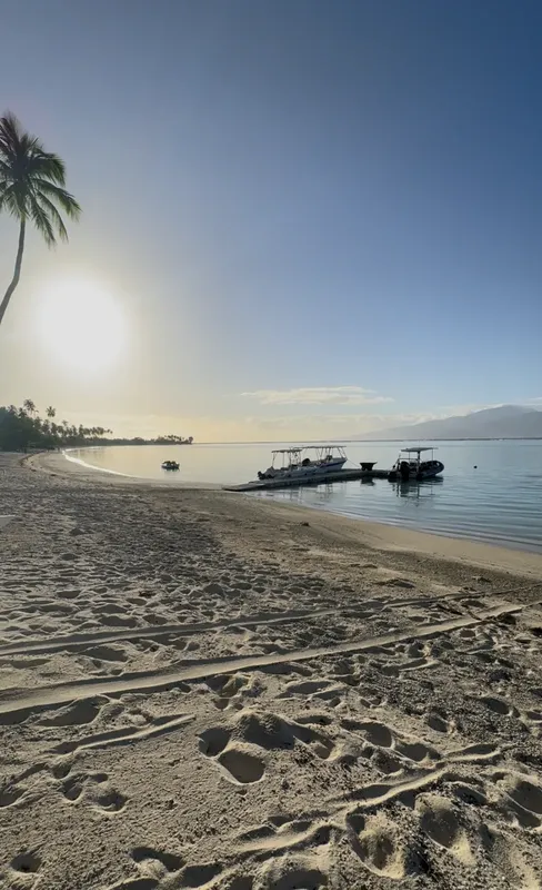 Plage de sable avec bateaux amarrés et ciel bleu clair