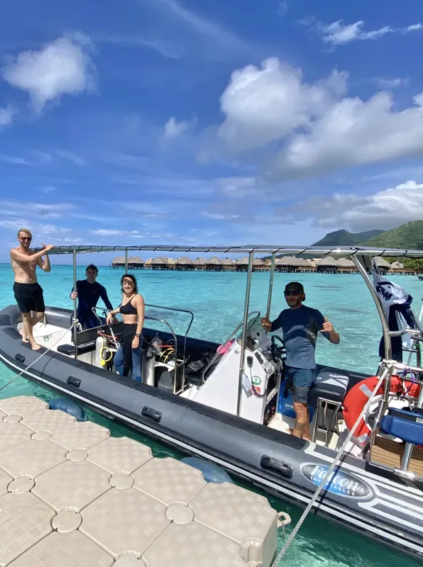Personnes à bord d'un bateau semi-rigide sur une eau turquoise claire