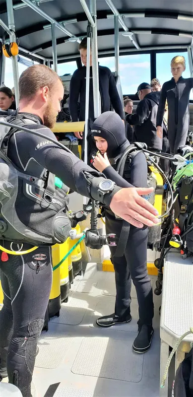 Plongeurs en combinaison se préparent à bord d'un bateau pour une sortie