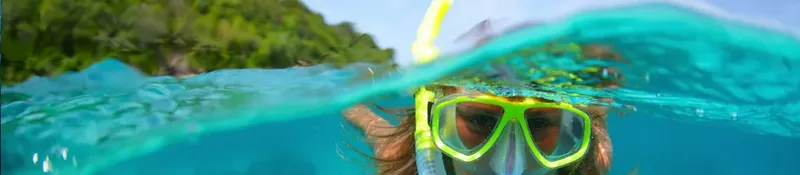 Visage d'une personne avec masque de plongée, eau turquoise, végétation