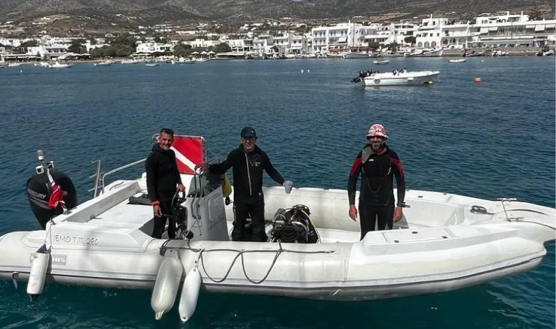 Trois plongeurs équipés se tiennent debout sur un bateau semi-rigide blanc