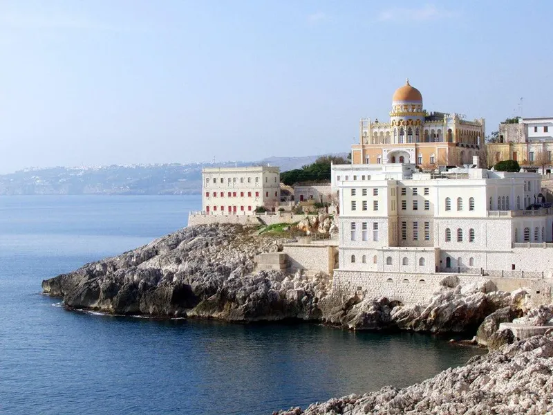 Vue côtière avec bâtiments colorés et falaise rocheuse au bord de mer