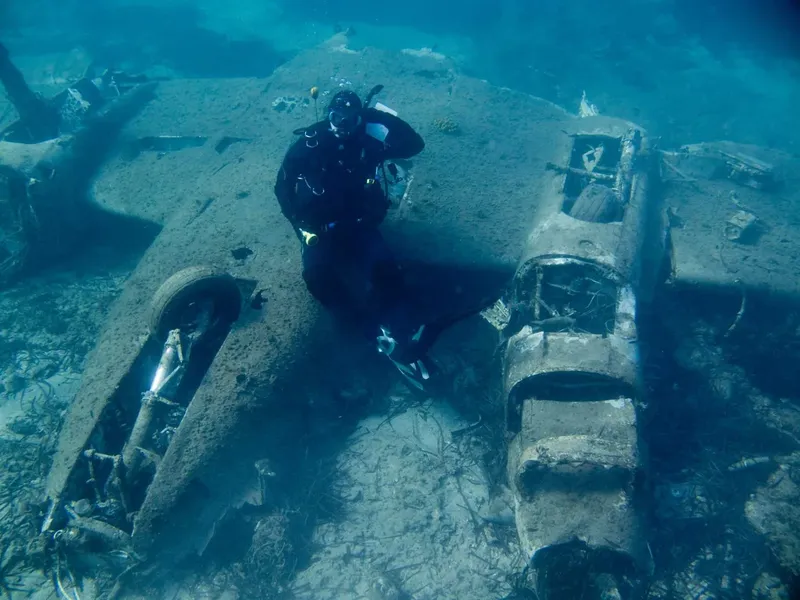 Plongeur explorant l'épave d'un avion coulé au fond de la mer