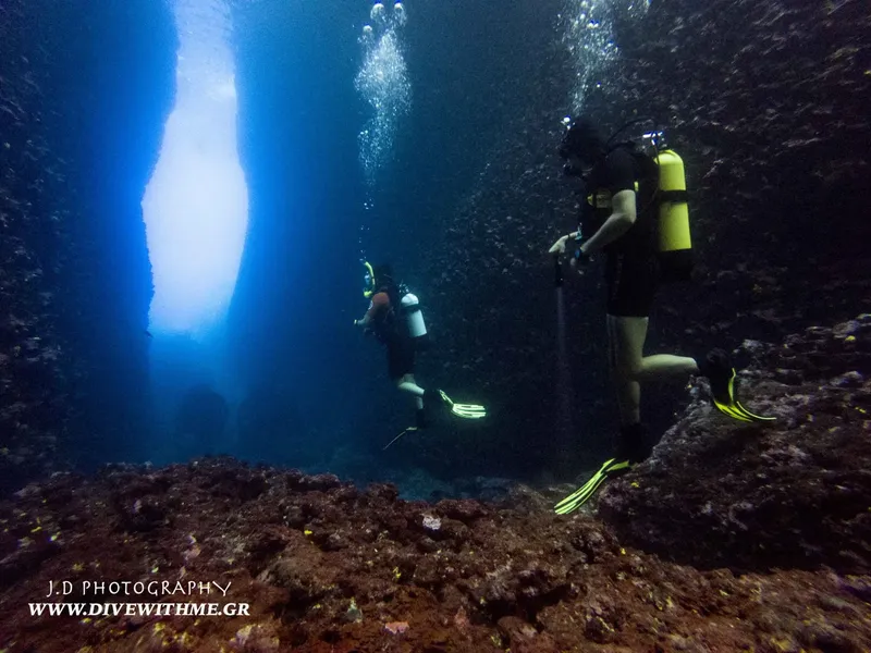 Deux plongeurs explorent une grotte sous-marine avec des rayons de lumière