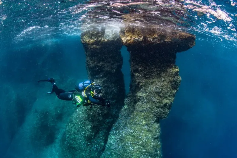 Plongeur explorant une structure rocheuse sous-marine en pleine lumière