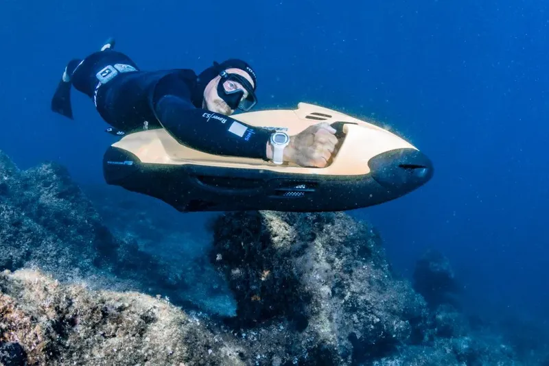 Plongeur utilisant un scooter sous-marin au-dessus d'un fond rocheux
