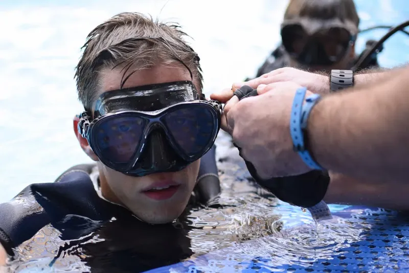 Un plongeur se fait ajuster son masque par un moniteur en mer