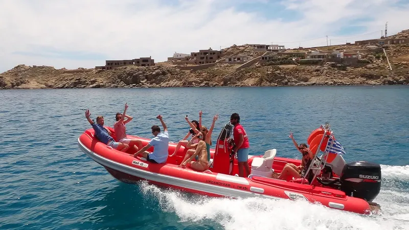 Groupe de personnes enthousiastes à bord d'un bateau pneumatique rouge en mer