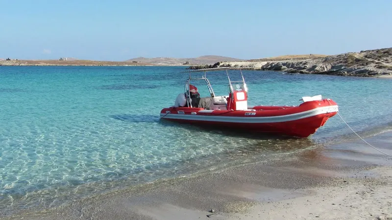Bateau pneumatique rouge et blanc échoué sur une plage de sable