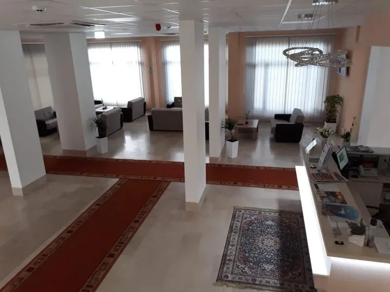Salle d'attente lumineuse avec canapés, tapis et comptoir d'accueil