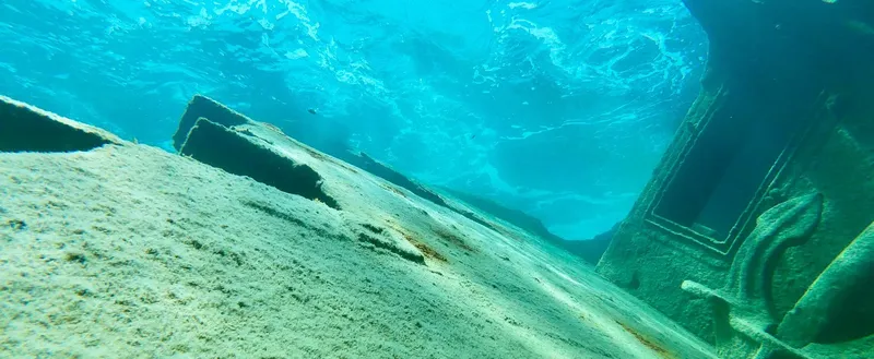 Epave de bateau coulee, sable et lumière bleutée sous l'eau