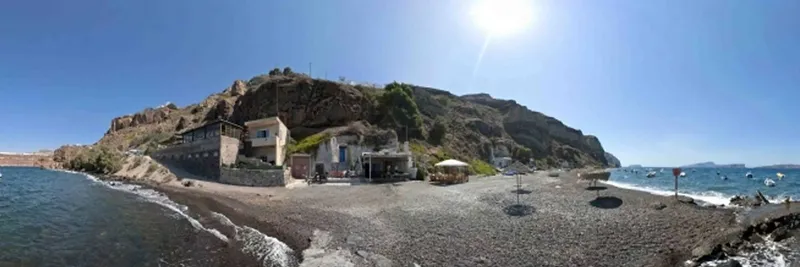 Plage de galets, bâtiments du centre de plongée, mer et montagnes