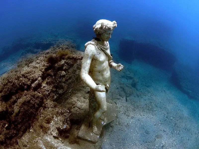 Statue antique immergée dans une eau claire et sableuse