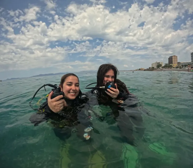 Deux plongeuses souriantes flottent à la surface de l'eau turquoise