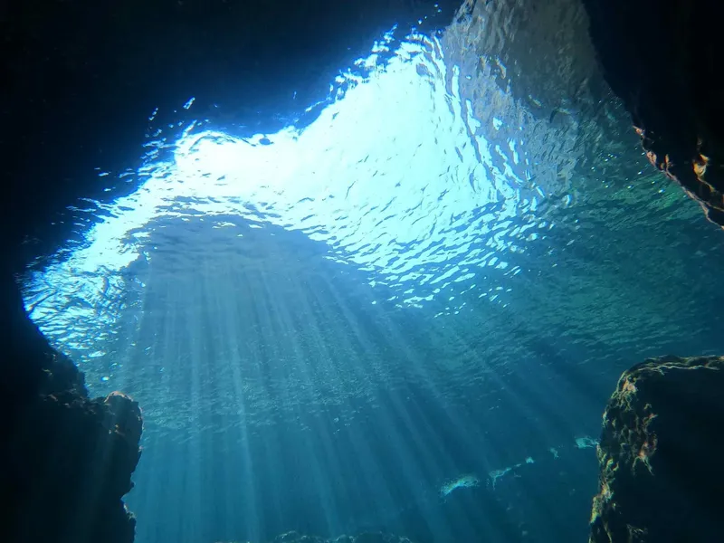 Rayons de soleil perçant la surface de l'eau dans une grotte sous-marine