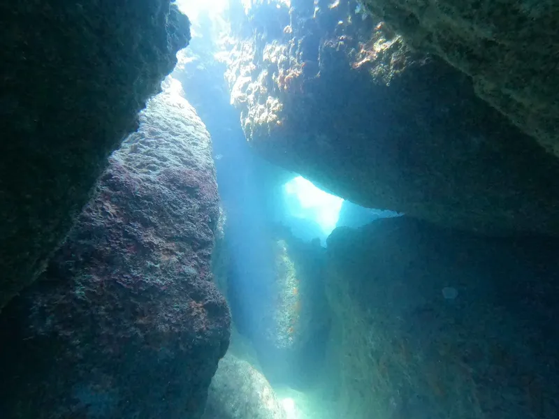 Vue sous-marine d'une grotte rocheuse éclairée par le soleil