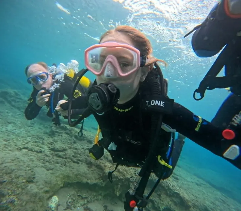 Deux plongeuses souriantes prennent un selfie sous l'eau en mer