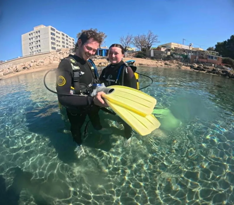 Deux plongeurs souriants dans l'eau claire avec leur palme jaune