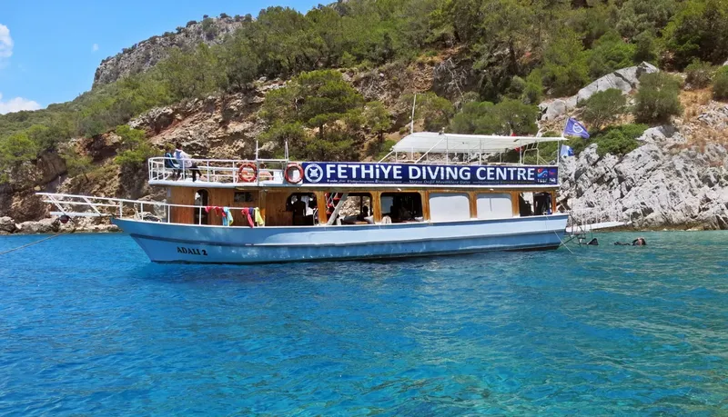 Bateau de plongée amarré dans une crique turquoise avec des équipements