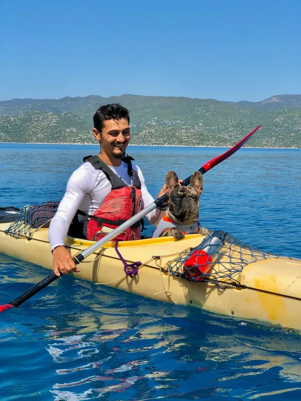 Homme souriant en kayak avec un bouledogue français sur l'eau