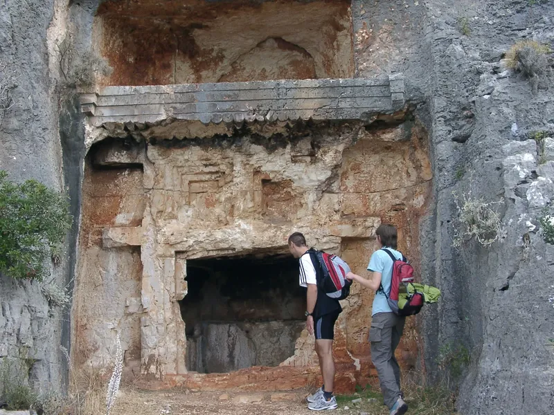 Deux personnes devant une entrée de grotte taillée dans la roche