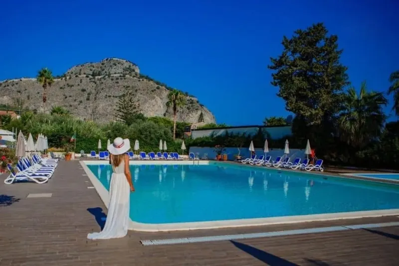 Femme en robe blanche près d'une piscine avec vue sur montagne