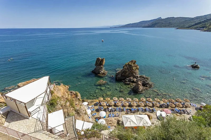 Vue aérienne d'une plage avec des rochers et une structure blanche
