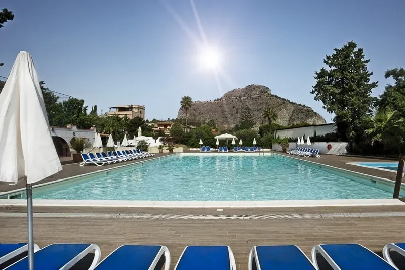 Piscine extérieure avec transats et parasols, journée ensoleillée et végétation