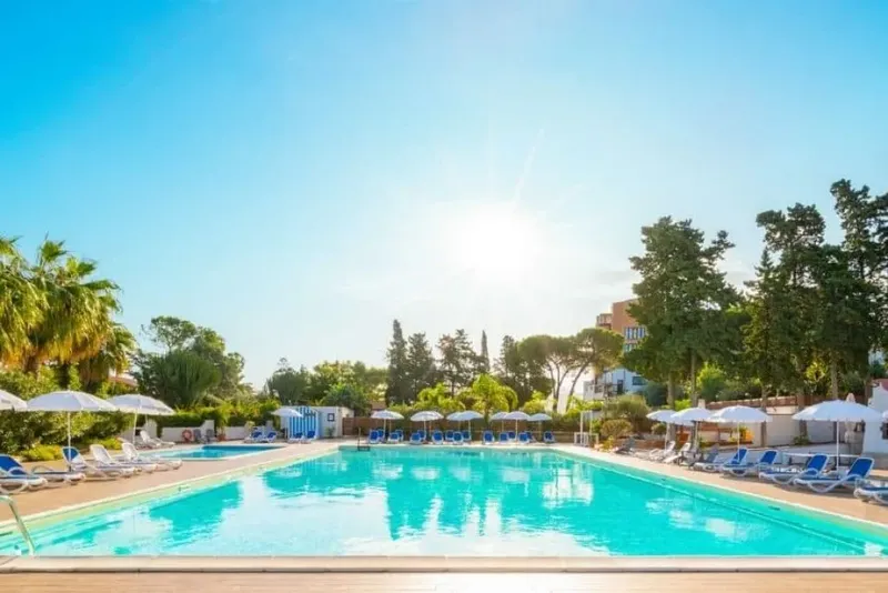 Piscine d'un centre de vacances avec transats et parasols ensoleillés