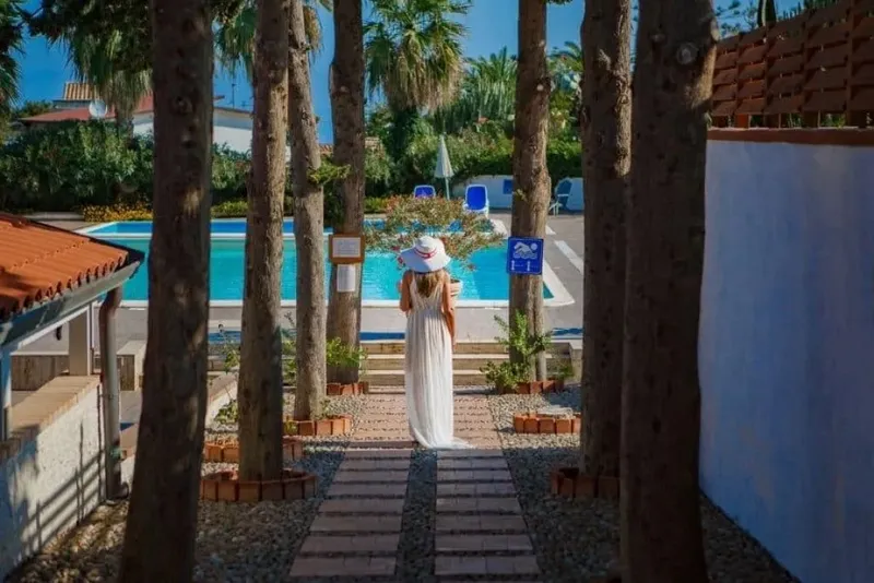 Femme en robe blanche devant une piscine dans un cadre tropical
