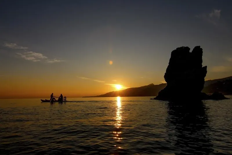 Personnes sur un bateau au coucher du soleil en mer
