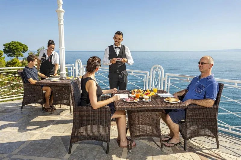 Famille prenant le petit déjeuner en terrasse avec vue sur la mer