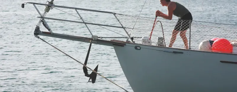 Une personne manipule une corde sur le pont d'un bateau en mer