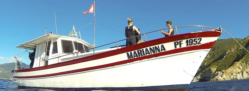 Bateau de plongée blanc et rouge avec deux personnes à bord