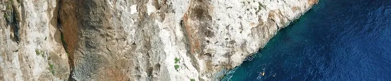 Vue sous-marine d'une paroi rocheuse avec eau turquoise et quelques plongeurs