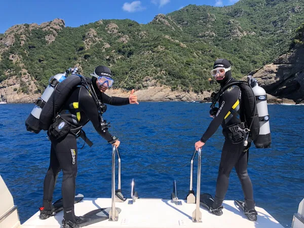 Deux plongeurs équipés sur un bateau, prêts pour une immersion