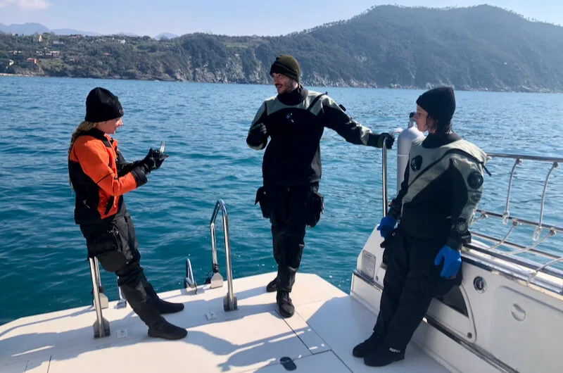 Trois plongeurs équipés sur le pont d'un bateau en mer