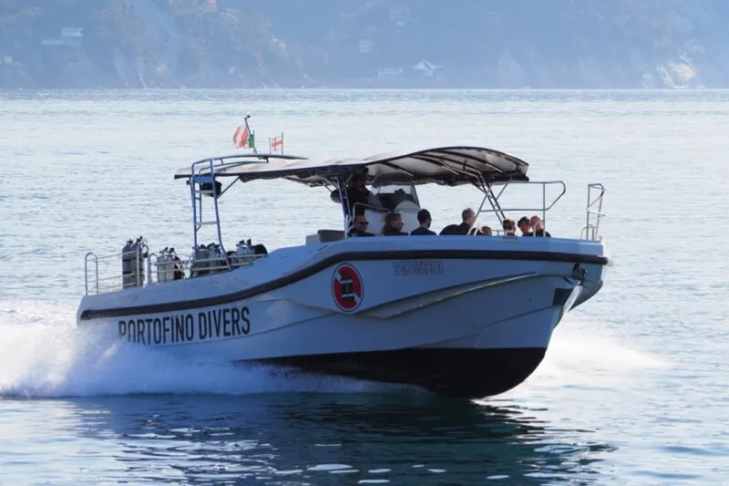Bateau de plongée blanc avec des passagers naviguant sur une mer bleue