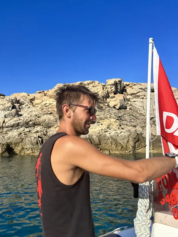Jeune homme souriant manipule une corde sur un bateau en mer
