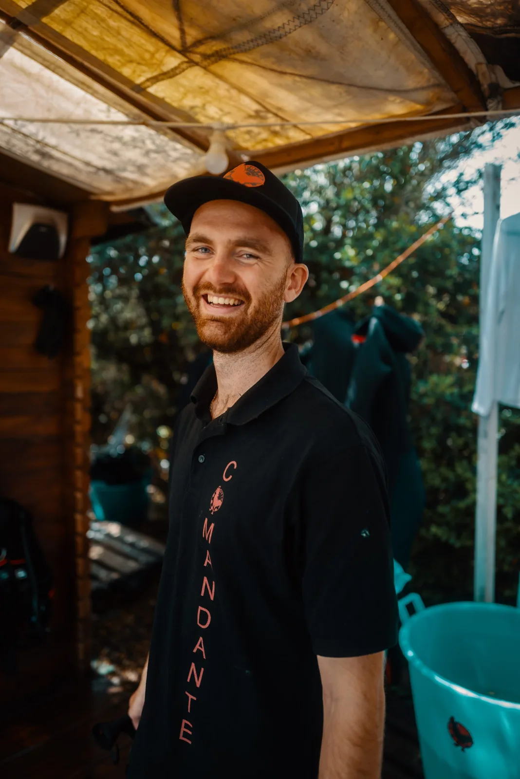 Un homme souriant porte une casquette et un polo noir