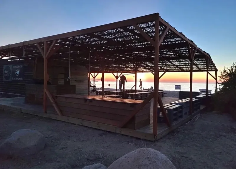 Structure en bois abritant une terrasse avec des personnes au loin