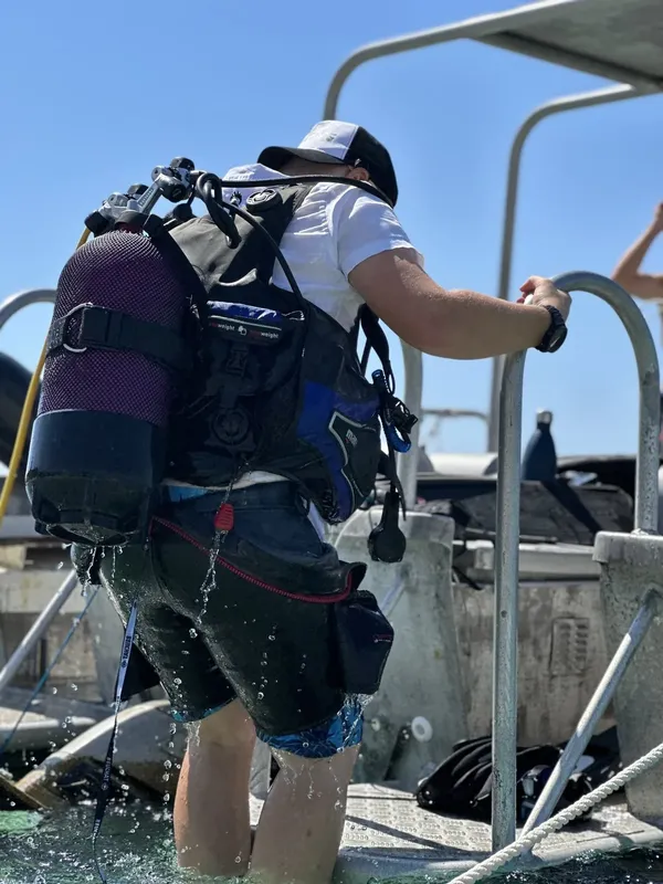 Plongeur s'équipant sur un ponton avec bouteilles et gilet stabilisateur