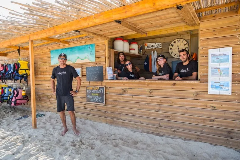 Equipe souriante devant le comptoir d'un centre de sports nautiques sur plage